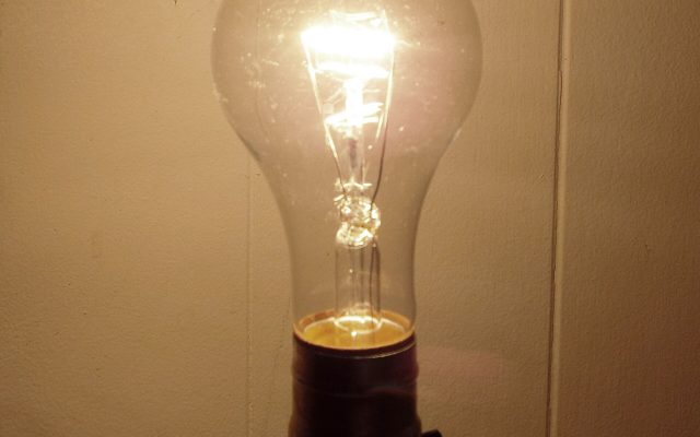 A glowing incandescent light bulb with visible filament