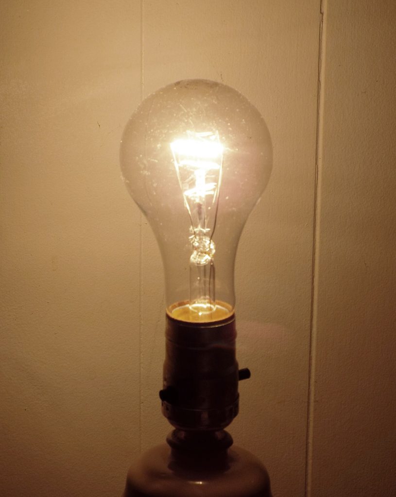 A glowing incandescent light bulb with visible filament