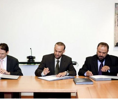 A hand signing a contract document with a pen